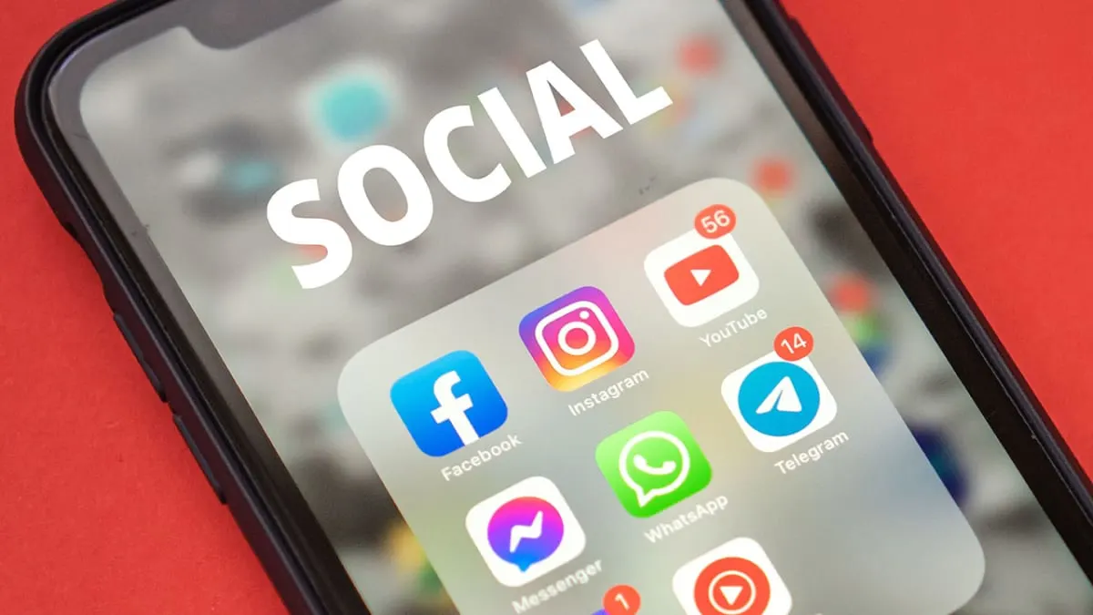 Phone screen showing a folder of social media apps including Facebook, Instagram, YouTube and WhatsApp
